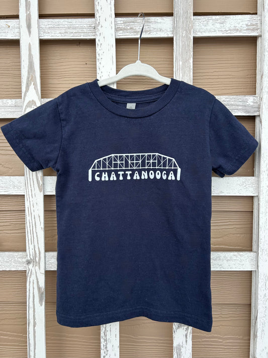 Navy blue t-shirt with 'Chattanooga' design on a hanger against a wooden lattice background